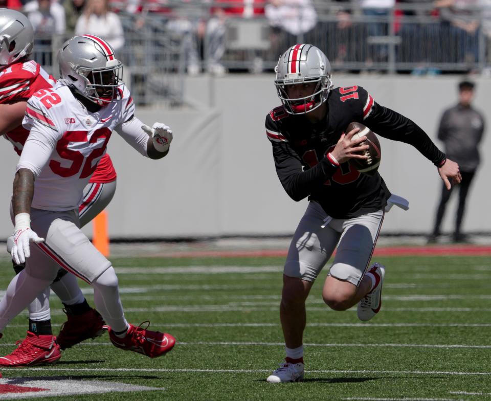 April 13, 2024; Columbus, Ohio, USA; 
Ohio State Buckeyes quarterback Julian Sayin (10) runs the football for the scarlet team while pursued by defensive end Josh Mickens (52) of the gray team during the first half of the LifeSports spring football game at Ohio Stadium on Saturday.