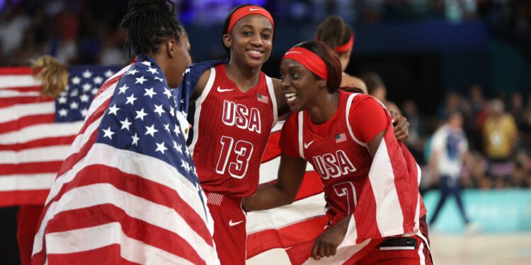 PARIS, FRANCE - AUGUST 11: Jackie Young #13, Kahleah Copper #7, and Chelsea Gray #8 of Team United States celebrate after their team's victory against Team France during the Women's Gold Medal game between Team France and Team United States on day sixteen of the Olympic Games Paris 2024 at Bercy Arena on August 11, 2024 in Paris, France. (Photo by Matthew Stockman/Getty Images)