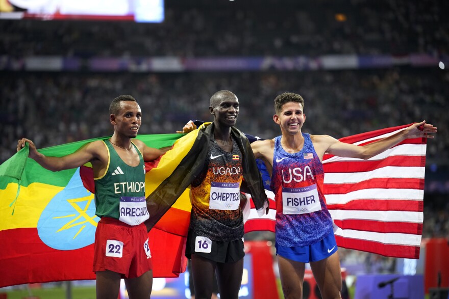 Gold medalist Joshua Cheptegei, of Uganda, poses with silver medalist Berihu Aregawi, of Ethiopia, left, and bronze medalist Grant Fisher, of the United States, after the men's 10,000-meter final at the 2024 Summer Olympics, Friday, Aug. 2, 2024, in Saint-Denis, France.