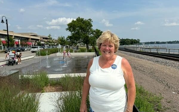 A woman in a white tank top smiles for a photo