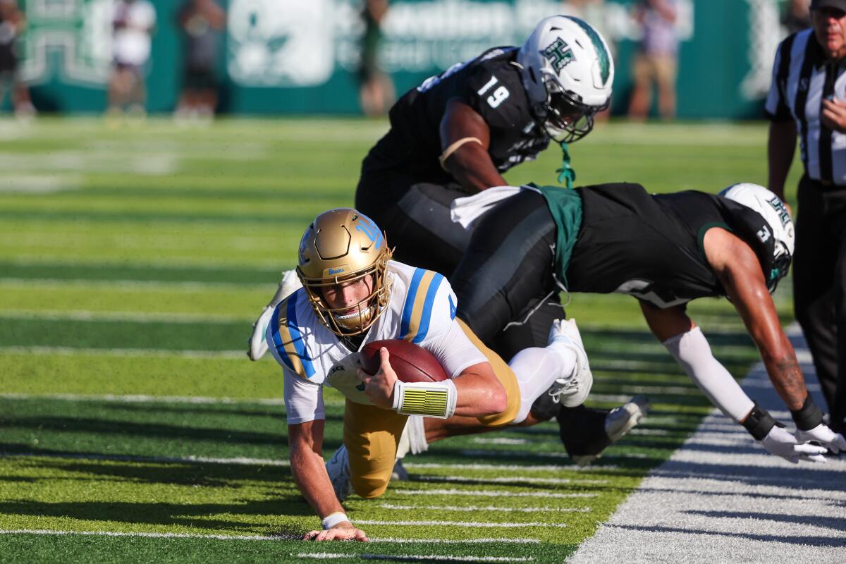 UCLA quarterback Ethan Garbers dives forward as he is pushed down by Hawaii’s Jalen Smith.