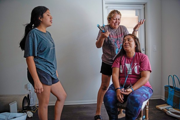 Valentina Castillo Solache 20, left, speaks while Karen Larios 42, center, does Maribel Solache's hair, as friends help clean out her apartment. (Alejandro Tamayo / The San Diego Union-Tribune)