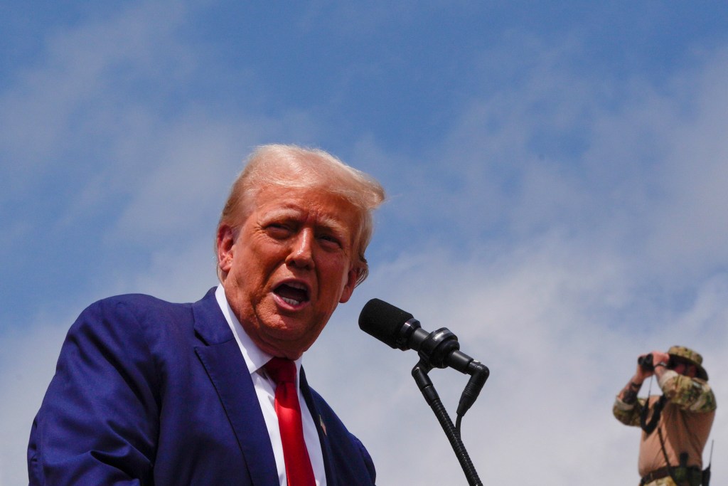 Former President Donald Trump speaking into a microphone at a campaign rally at North Carolina Aviation Museum in 2024