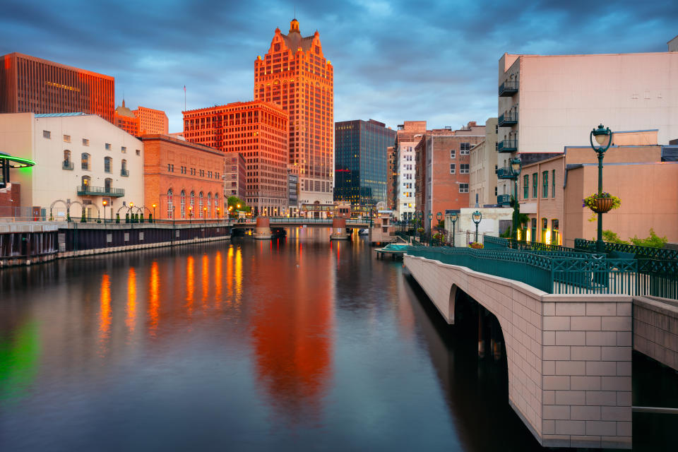 Cityscape image of downtown Milwaukee, Wisconsin, USA with reflection of the skyline in Milwaukee River at summer sunset.