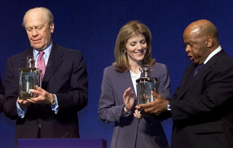 Former U.S. President Gerald Ford (L) and U.S. Congressman John Lewis (D-GA) admire their John F. Kennedy Profile in Courage awards with JFK's daughter Caroline Kennedy Schlossberg during presentation ceremonies May 21, 2001 at the JFK Presidential Library in Boston. Ford was honored for pardoning former President Richard Nixon in 1974, while Lewis was given the first ever JFK 