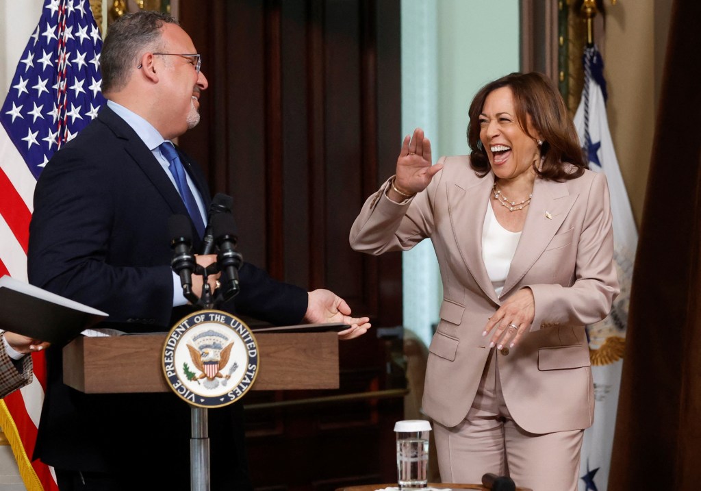 U.S. Vice President Kamala Harris surprising Education Secretary Miguel Cardona at a podium, about to swear in commissioners for a White House initiative for Hispanics in Washington.