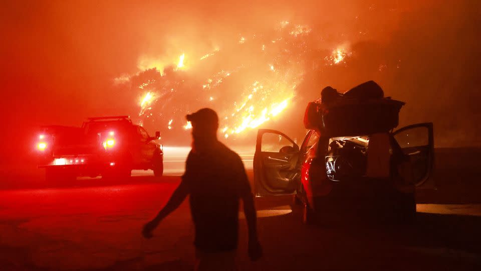 A resident walks by his car packed with belongings as Highway 330 is engulfed by the Line Fire near Running Springs, California, on September 7, 2024. - David Swanson/AFP/Getty Images