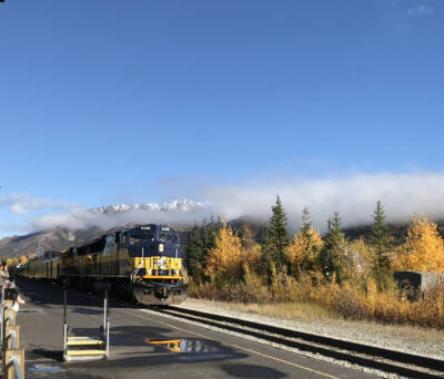 Blue and gold passenger train arrives at the station. Traveling from winter to fall.