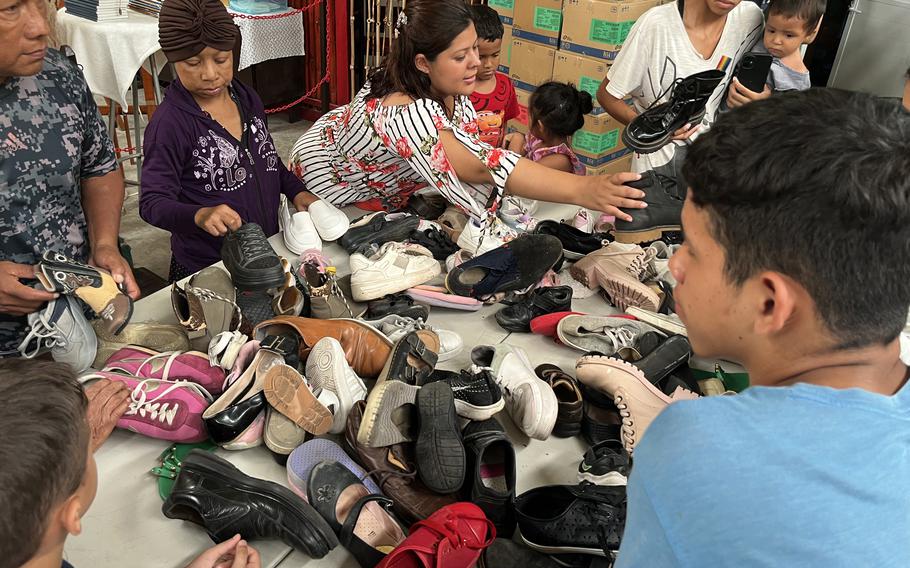 Migrants at shelter look through donated shoes