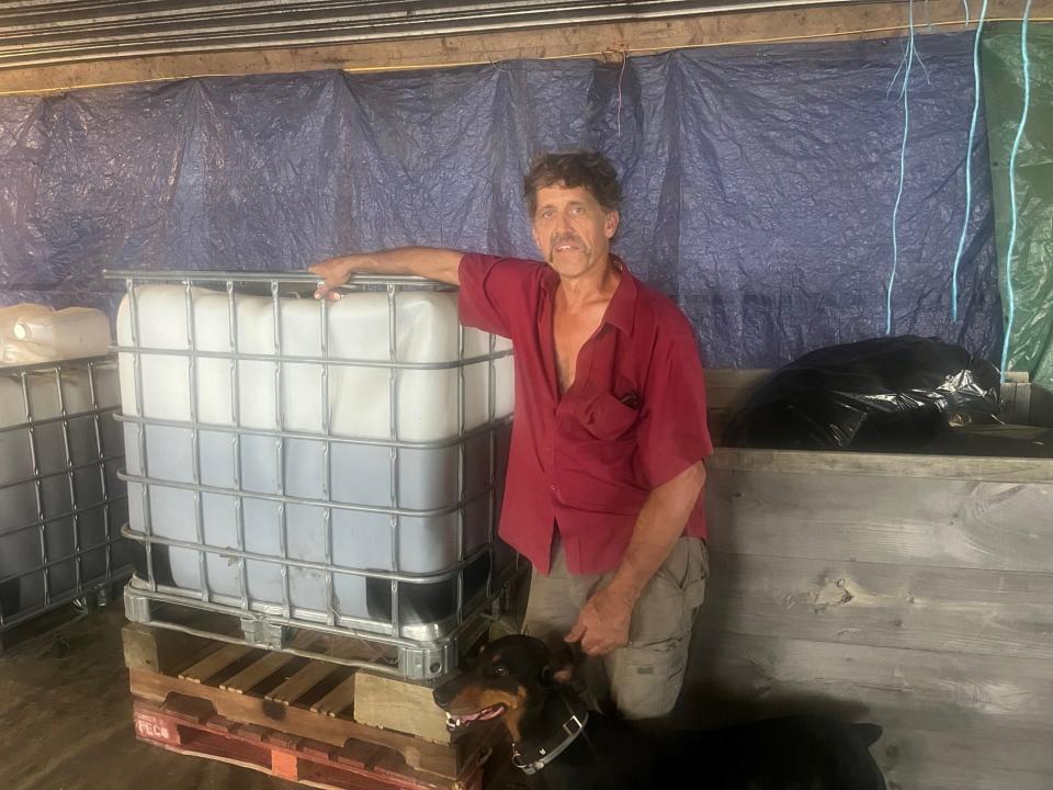 John Rodgers with a container of a liquid seaweed extract he uses to accelerate the growth of hemp plants at his farm in West Glover, as seen on July 28, 2023.