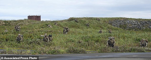 U.S. Army soldiers maneuver through the thick terrain of desolate island