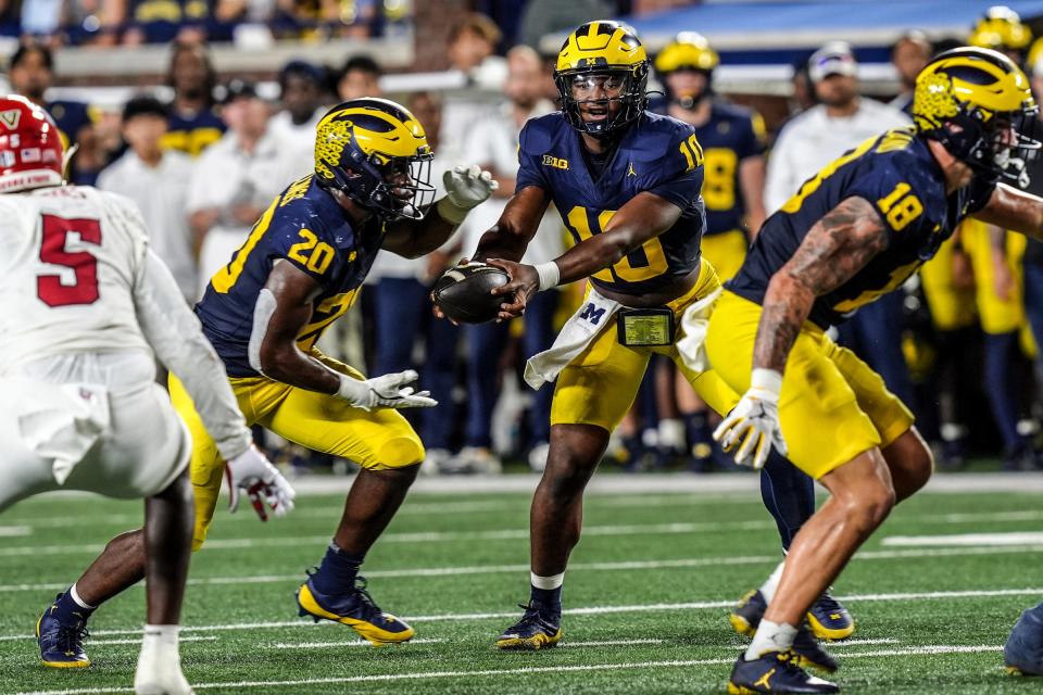 Michigan quarterback Alex Orji (10) hands the ball to Michigan running back Kalel Mullings (20) during the first half against Fresno State at Michigan Stadium at Michigan Stadium in Ann Arbor on Saturday, Aug. 31, 2024.