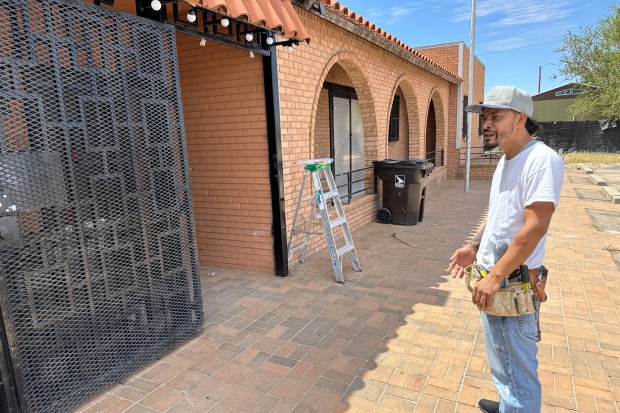 Luis Soto of Sunland Park, N.M. works on wiring and talks outside at his cannabis dispensary