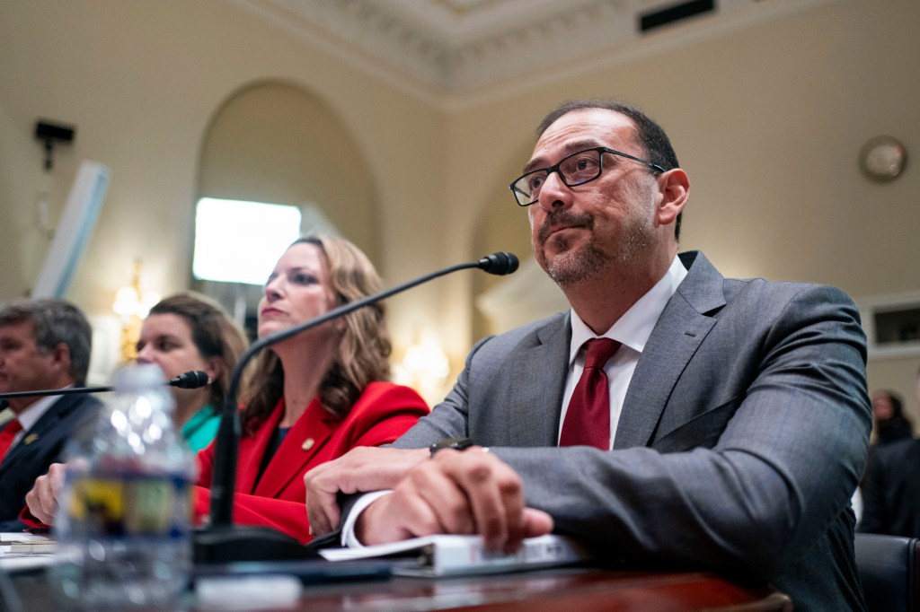 Arizona Secretary of State Adrian Fontes sitting at a table with a microphone during a House Administration Committee hearing in Washington, DC