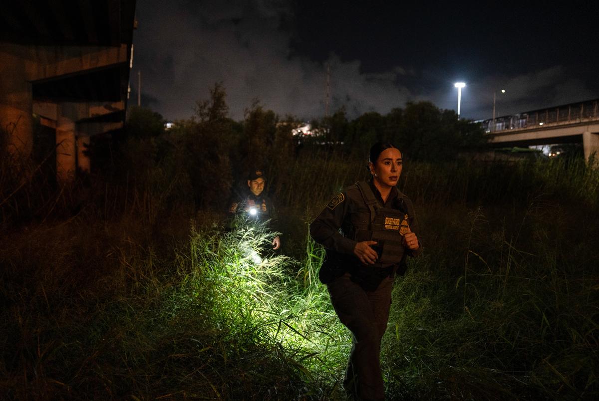 Christina Smallwood, foreground, and Andrés García, Border Patrol agents and Public Affairs officers look for migrants underneath the vehicular McAllen-Hidalgo International Bridge in Hidalgo, Texas, early Friday, Aug. 9, 2024.