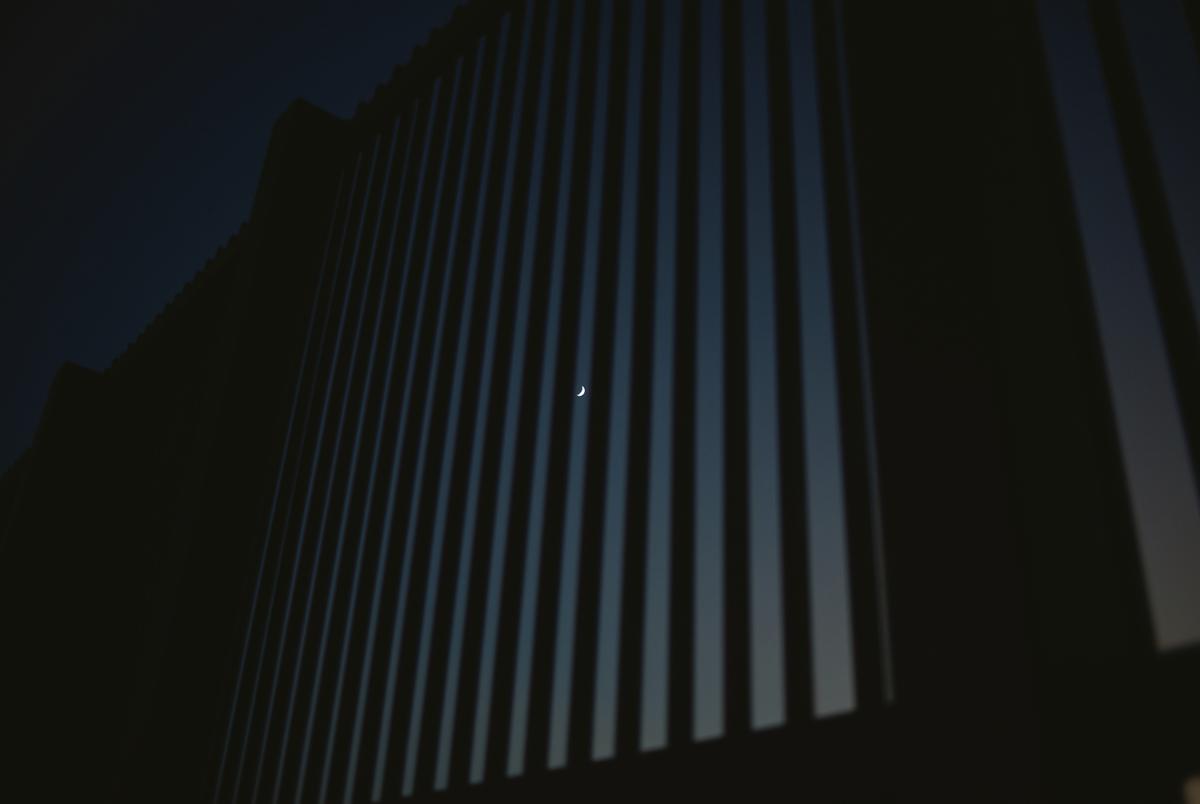 The moon is seen behind the border wall in Eagle Pass, Texas, on Friday evening, Aug. 9, 2024.