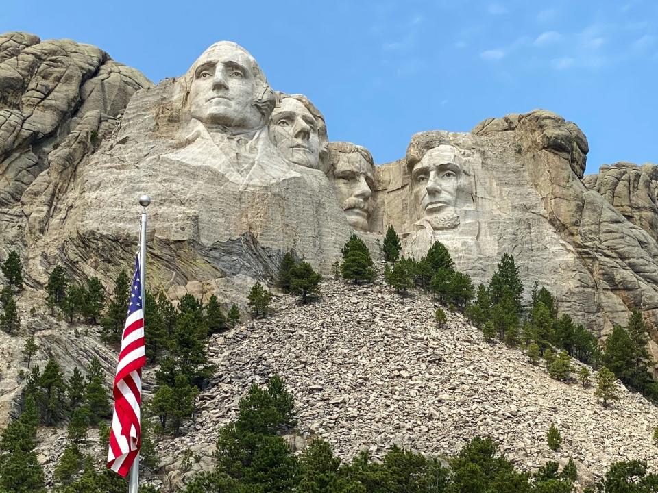 A view of Mount Rushmore with an American flag in front of it.