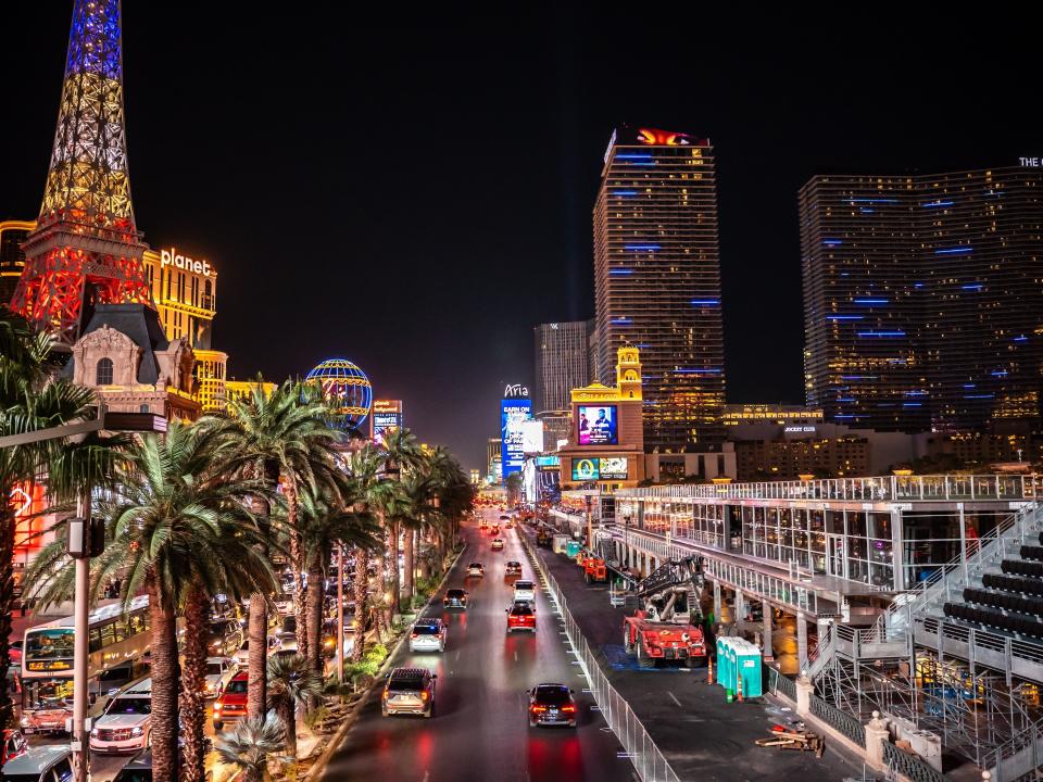 A view of the Las Vegas strip at night with lit-up buildings and cars roaming the streets.