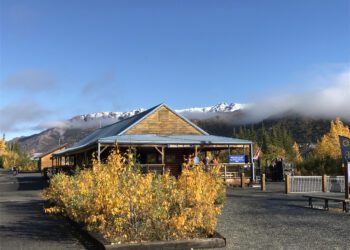 Train depot with snow capped mountain in background. Traveling from winter to fall.