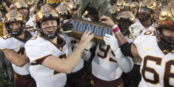 IOWA CITY, IOWA- OCTOBER 21:  Quarterback Athan Kaliakmanis #8  of the Minnesota Golden Gophers celebrates with teammates as they take the Floyd of Rosedale trophy after their match-up against the Iowa Hawkeyes  at Kinnick Stadium on October 21, 2023 in Iowa City, Iowa.  (Photo by Matthew Holst/Getty Images)