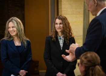 Two women stand and receive applause