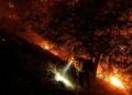 A firefighter walks up a hill as the Bridge Fire burns near homes in Wrightwood, California, on Tuesday. - Jae C. Hong/AP