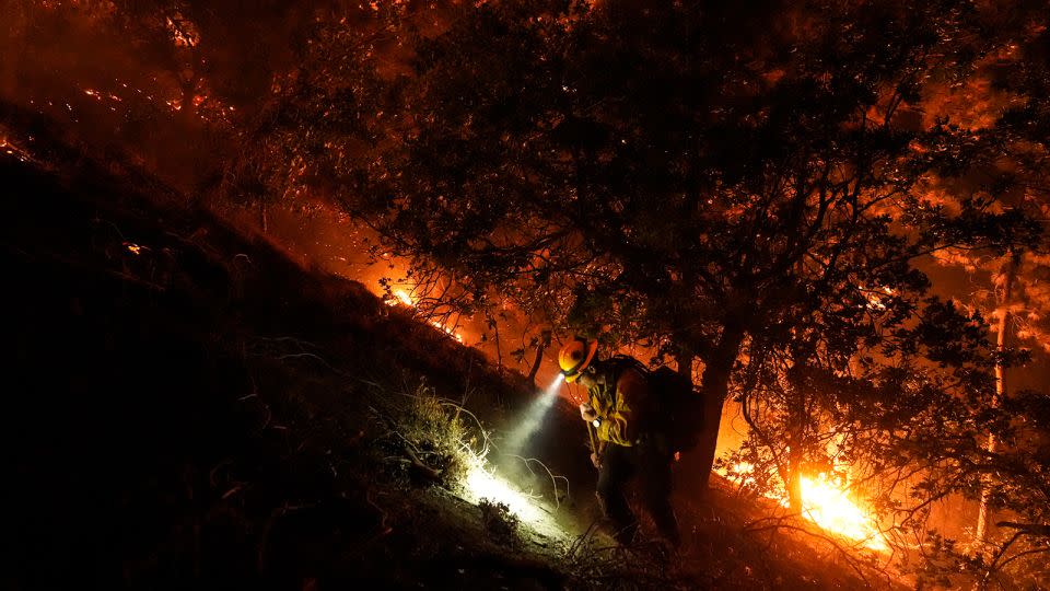 A firefighter walks up a hill as the Bridge Fire burns near homes in Wrightwood, California, on Tuesday. - Jae C. Hong/AP