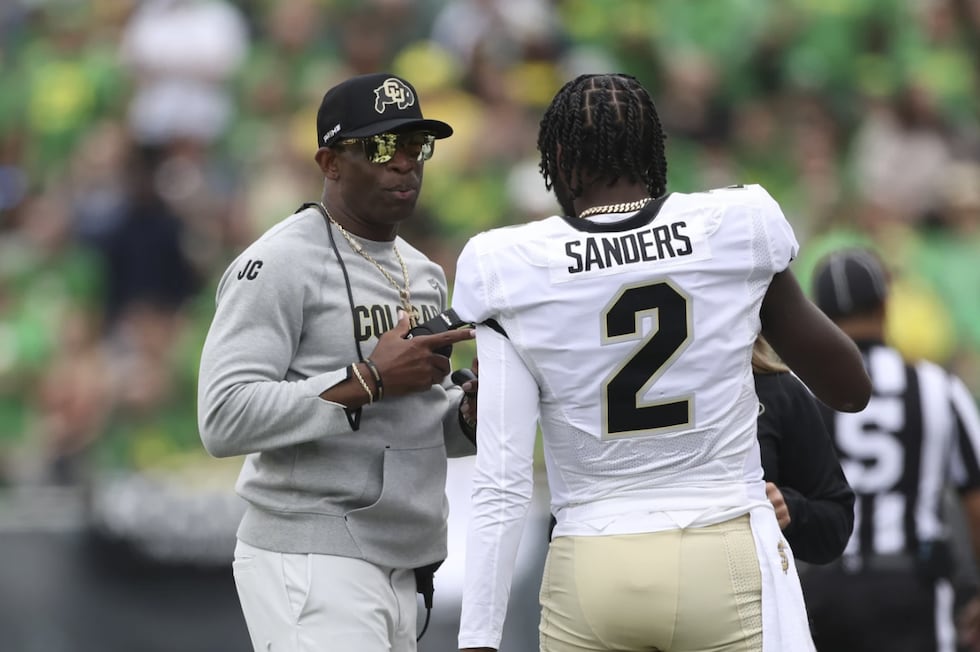 Colorado head coach Deion Sanders talks with his son and quarterback Shedeur Sanders during...