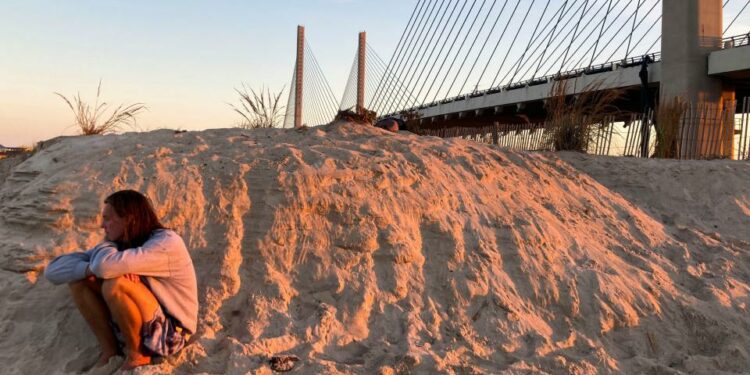 A man watches the surf and surfers as a day ends under the Indian River Inlet Bridge at Delaware Seashore State Park, Saturday, Sept. 2, 2023, during the unofficial end to summer, Labor Day weekend.