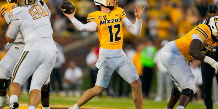 Sep 21, 2024; Columbia, Missouri, USA; Missouri Tigers quarterback Brady Cook (12) throws a touchdown pass against the Vanderbilt Commodores during overtime at Faurot Field at Memorial Stadium. Mandatory Credit: Jay Biggerstaff-Imagn Images