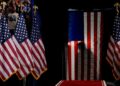 The silhouette of Republican presidential nominee former President Donald Trump is seen as he pauses behind an American Flag as he arrives to speak at a campaign rally at the Mohegan Arena at Casey Plaza, Saturday, Aug. 17. 2024, in Wilkes-Barre, Pa. (AP Photo/Carolyn Kaster)