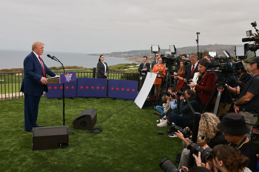 Former U.S. President Donald Trump speaking to reporters off the coast of the Pacific Ocean. Trump is on the left...