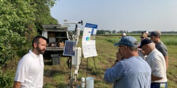 Men talk next to a weather station.