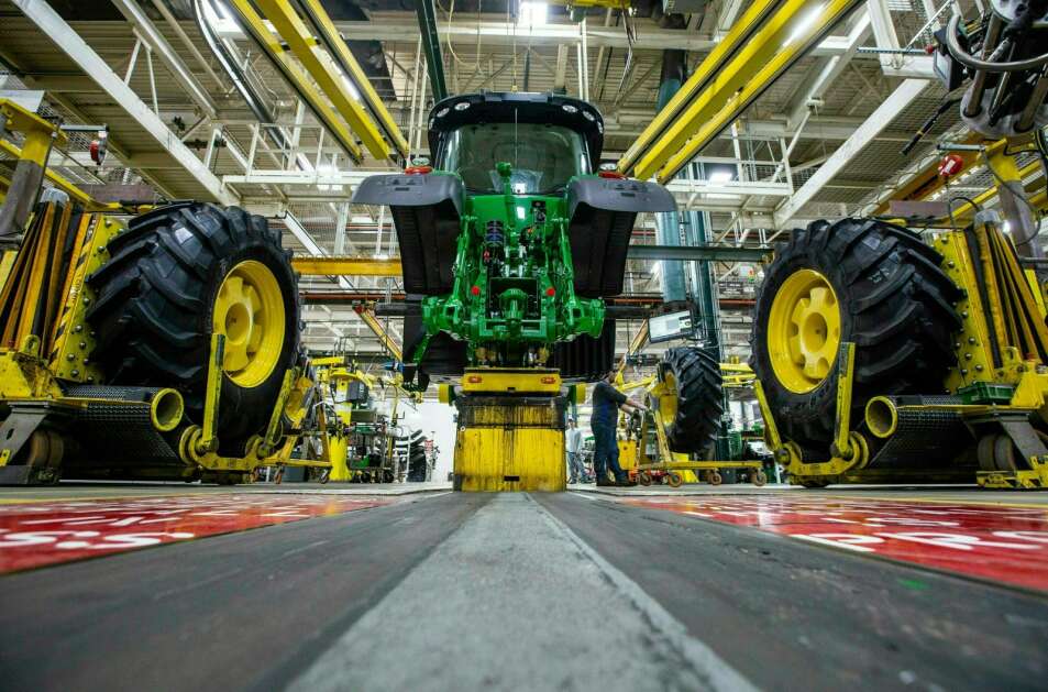 In this April 9, 2019 photo, wheels are attach as workers assemble a tractor at John Deere's Waterloo assembly plant. (Zach Boyden-Holmes/Telegraph Herald via AP, File)