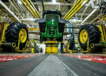 In this April 9, 2019 photo, wheels are attach as workers assemble a tractor at John Deere's Waterloo assembly plant. (Zach Boyden-Holmes/Telegraph Herald via AP, File)