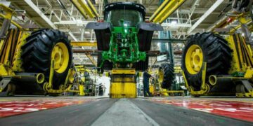 In this April 9, 2019 photo, wheels are attach as workers assemble a tractor at John Deere's Waterloo assembly plant. (Zach Boyden-Holmes/Telegraph Herald via AP, File)