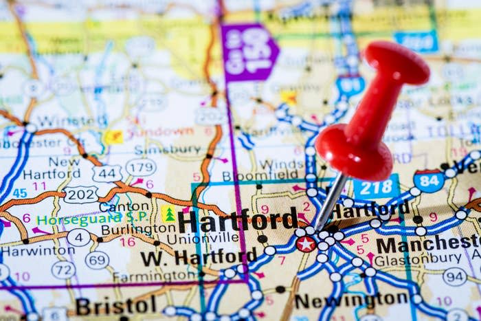 Close-up of a map showing Hartford, with a red pushpin marking the location. Nearby cities like New Hartford, Canton, and Manchester are also visible