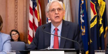 US Attorney General Merrick Garland speaking at a podium during a meeting of the Justice Department's Election Threats Task Force