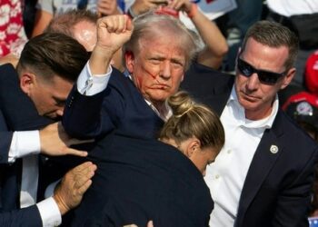 Republican candidate Donald Trump is seen with blood on his face surrounded by Secret Service agents as he is taken off the stage at a campaign event at Butler Farm Show Inc. in Butler, Pennsylvania, July 13, 2024. Donald Trump was hit in the ear in an apparent assassination attempt by a gunman at a campaign rally on Saturday, in a chaotic and shocking incident that will fuel fears of instability ahead of the 2024 US presidential election. (Photo by Rebecca DROKE / AFP)