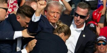 Republican candidate Donald Trump is seen with blood on his face surrounded by Secret Service agents as he is taken off the stage at a campaign event at Butler Farm Show Inc. in Butler, Pennsylvania, July 13, 2024. Donald Trump was hit in the ear in an apparent assassination attempt by a gunman at a campaign rally on Saturday, in a chaotic and shocking incident that will fuel fears of instability ahead of the 2024 US presidential election. (Photo by Rebecca DROKE / AFP)