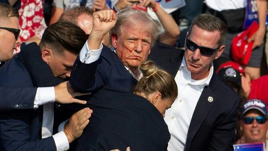 Republican candidate Donald Trump is seen with blood on his face surrounded by Secret Service agents as he is taken off the stage at a campaign event at Butler Farm Show Inc. in Butler, Pennsylvania, July 13, 2024. Donald Trump was hit in the ear in an apparent assassination attempt by a gunman at a campaign rally on Saturday, in a chaotic and shocking incident that will fuel fears of instability ahead of the 2024 US presidential election. (Photo by Rebecca DROKE / AFP)