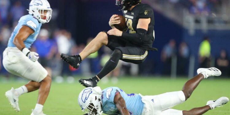 Lindenwood Lions quarterback Nate Glantz (18) jumps over Kansas Jayhawks safety Taylor Davis (27) in the fourth quarter of the game Thursday, August 29, 2024 at Children's Mercy Park.